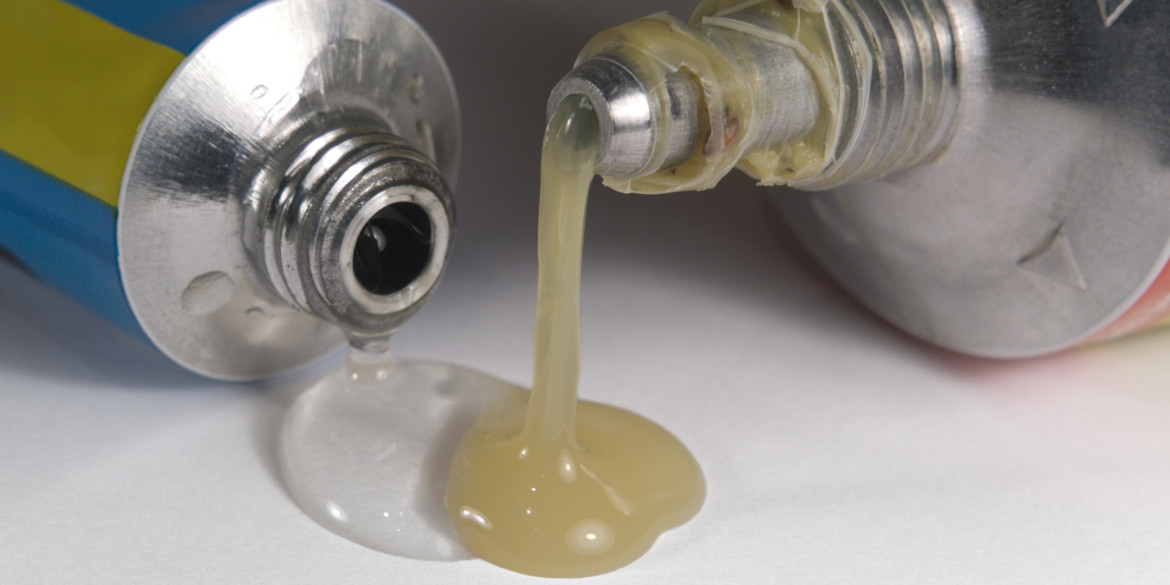 studio photography of two emplastic tube tips and flowing glue